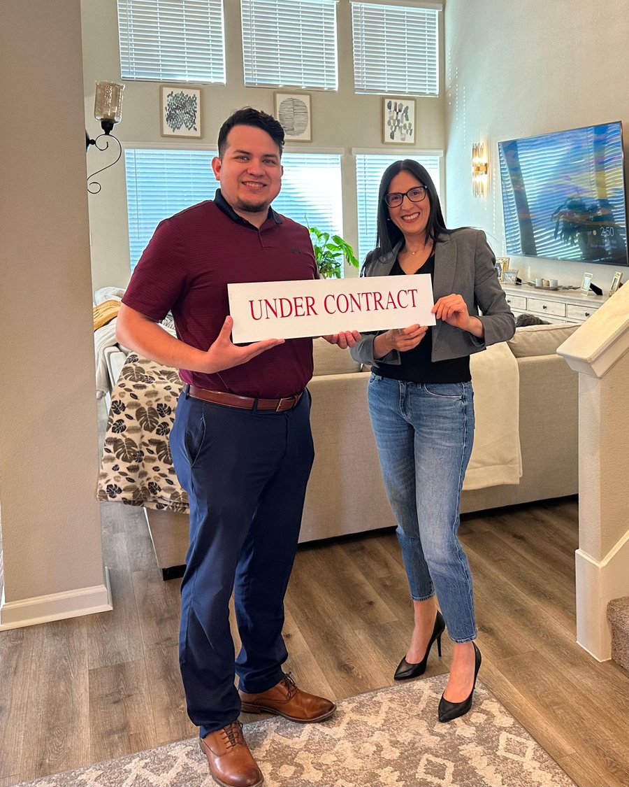 Juan Sanchez and Yary Diaz holding an Under Contract sign inside a home